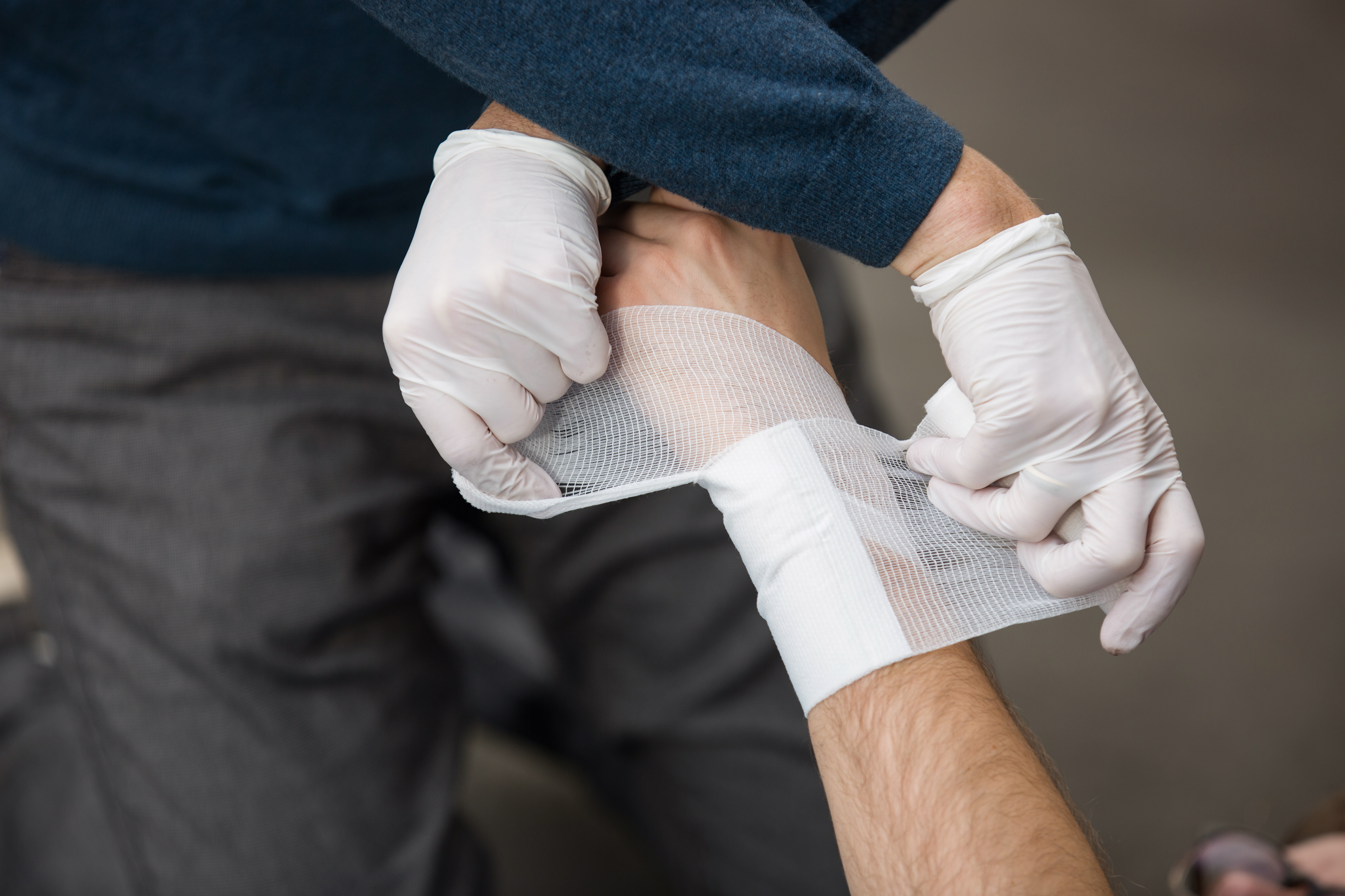 Erste_Hilfe-1543 (1).jpg Ein Mann leistet Erste-Hilfe und verbindet eine andere Person.