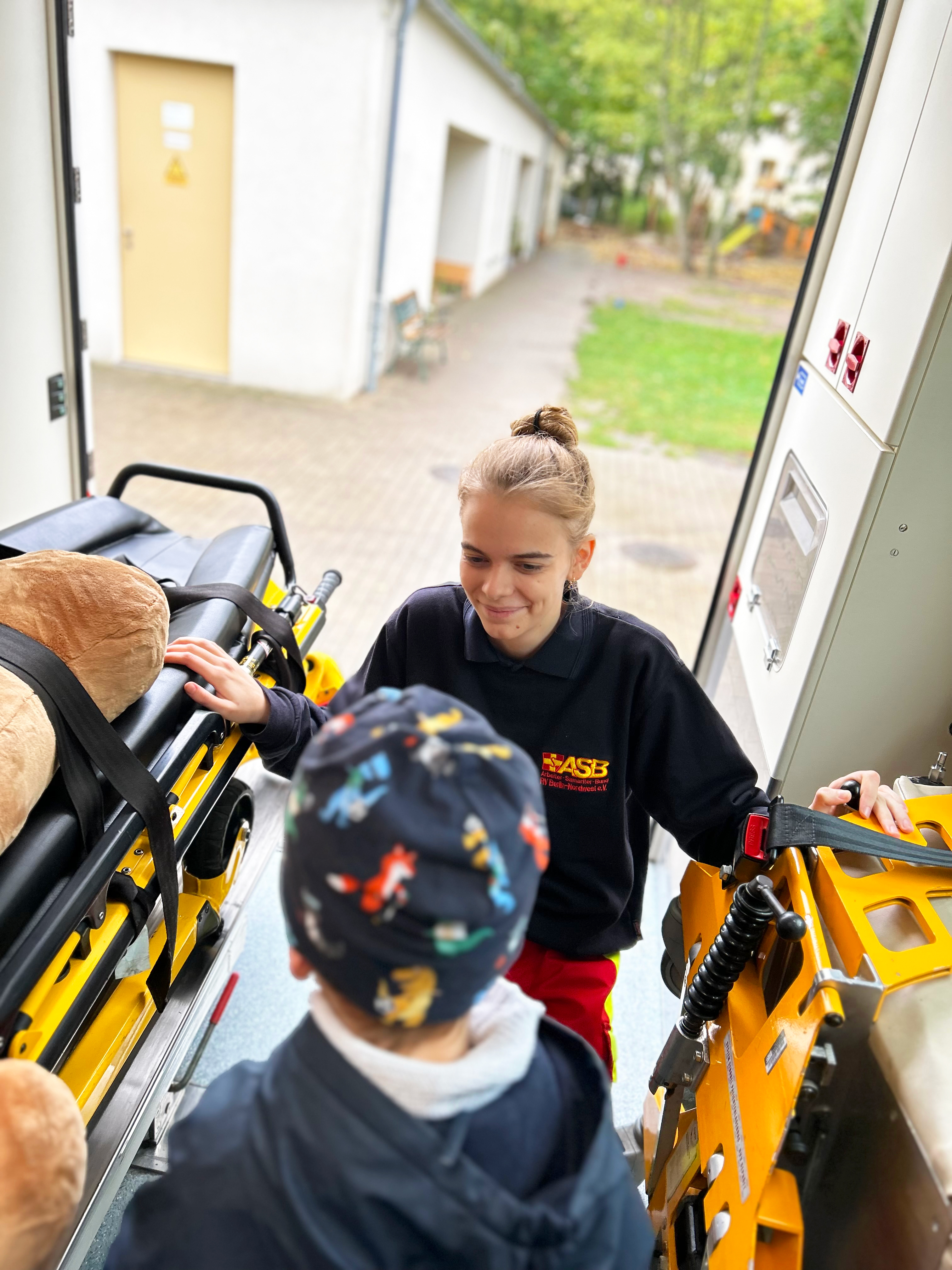 FSJlerin zeigt einem Kindergarten Kind bei einem Pflasterheld Kurs den RTW